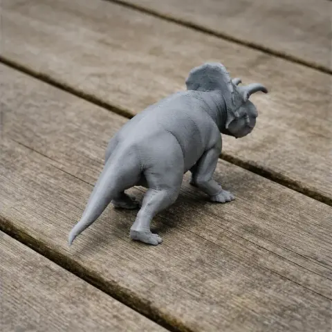 A 3D printed model of an Avaceratops dinosaur on a wooden surface.
