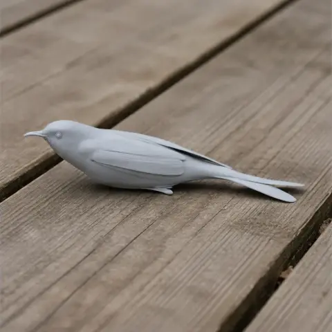 3D-printed light gray bird model with a long tail, resting on wooden planks.