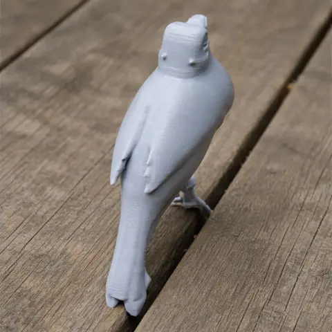 Gray 3D-printed bird figurine standing on a wooden surface, viewed from the back.