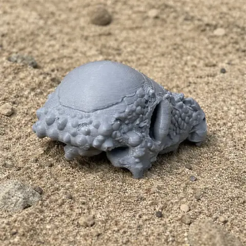 3D-printed Sanpasaurus skull replica on a sandy surface.