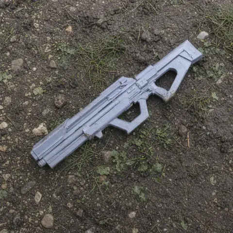 A gray, 3D-printed, futuristic rifle prop on muddy ground.