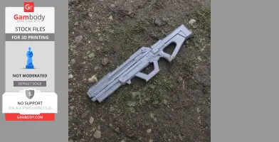 A gray 3D-printed futuristic weapon prop lies on earthy ground with sparse grass.