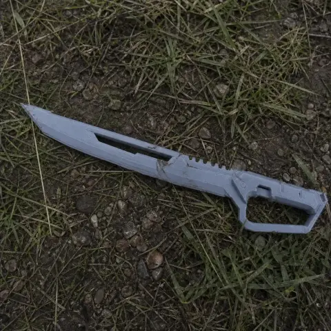 Futuristic machete prop from Cyberpunk 2077, crafted for 3D printing, lying on grass and gravel.