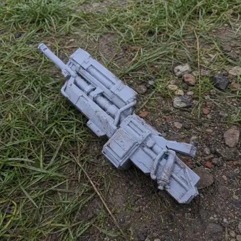 Futuristic HMG prop for cosplay, resting on grass and rocky ground.