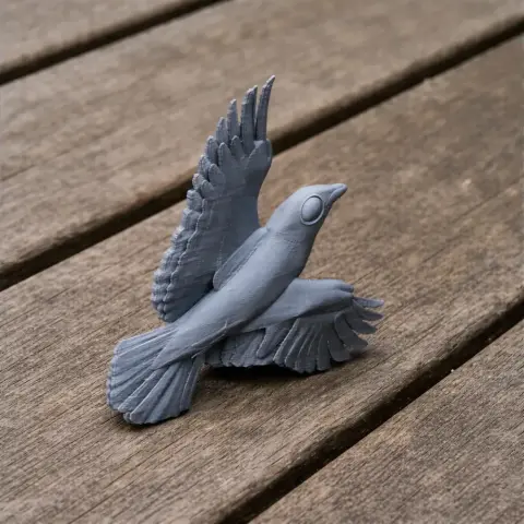 3D printed model of a bird, wings spread, on a wooden surface.