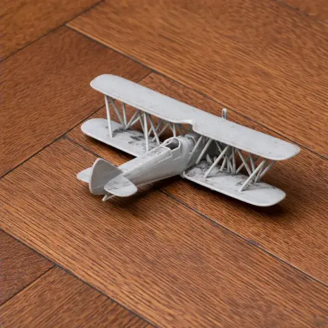 Gray 3D-printed model of a biplane on a wooden surface.