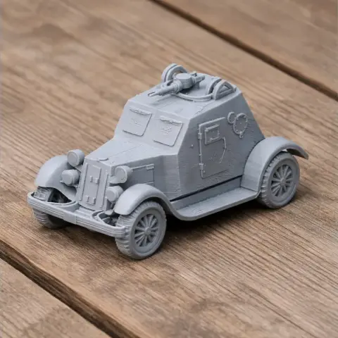 Gray 3D-printed model of an armored car with detailed features on a wooden surface.