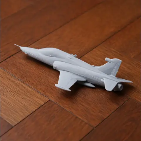 Gray 3D-printed BAE Hawk model aircraft on a wooden surface.