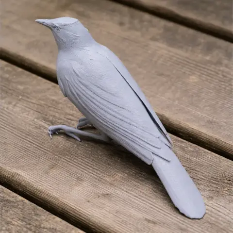 Gray 3D-printed starling model with detailed feathers, perched on wooden surface.