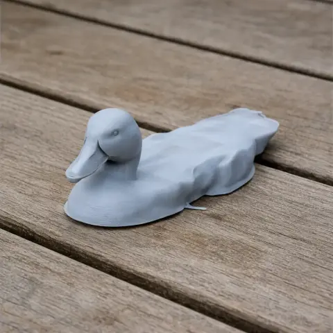 3D printed duck model with a smooth surface, resting on a wooden background.
