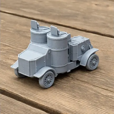 3D-printed model of an Austin armoured car with detailed turrets on a wooden surface.