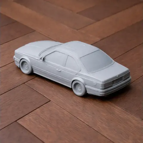 3D-printed BMW E24 model car in grey, displayed on a wooden surface.