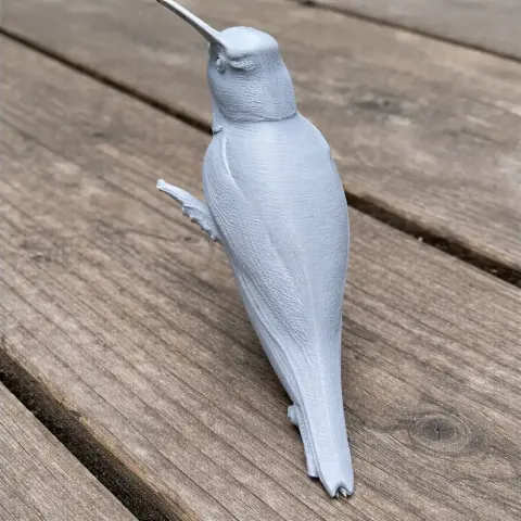 3D-printed model of a hummingbird perched on a branch, viewed from the back.
