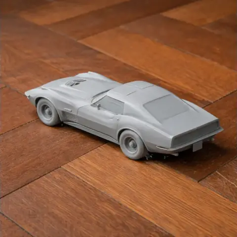 3D printed gray model of a Chevrolet Corvette C3 on a wooden surface.