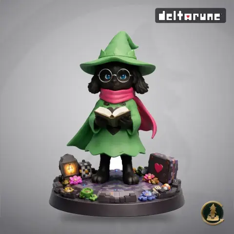 A character in a green robe and hat, holding a book, stands on a detailed base with colorful accents.