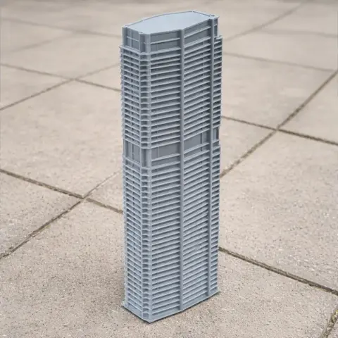 3D printed model of a modern skyscraper with detailed architectural features on a tiled surface.