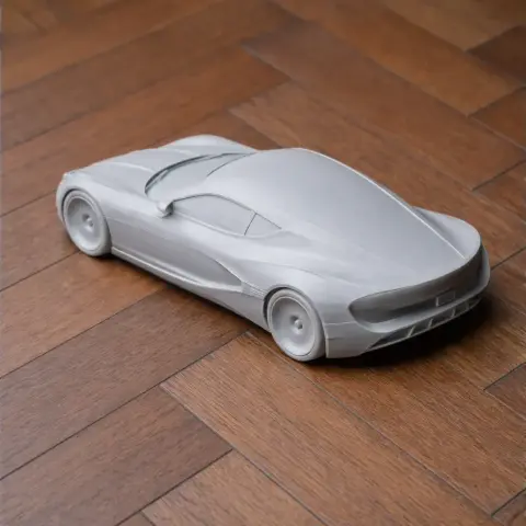 Sleek 3D-printed model of a futuristic car on a wooden surface.