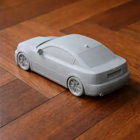 3D-printed scale model of a sleek, modern car on a wooden surface.