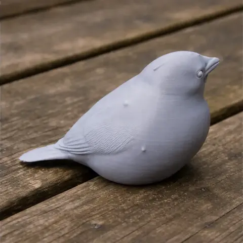 A 3D printed model of a sparrow, featuring detailed feathers, sitting on a wooden surface.
