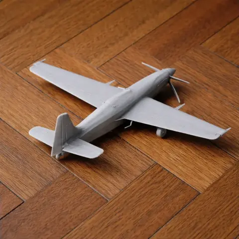 Gray 3D-printed model of a Corvus Racer 540 airplane on a wooden floor.
