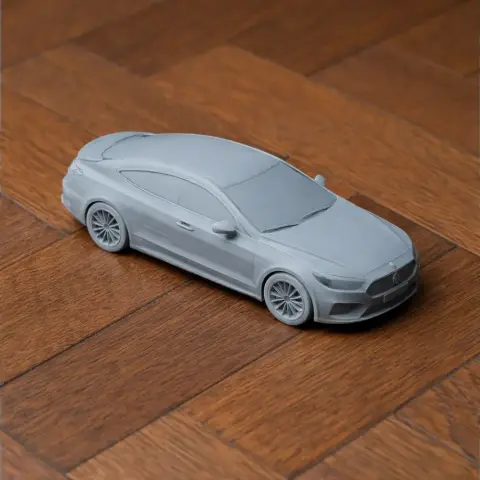 A detailed 3D printed model of a coupe car on a wooden surface.