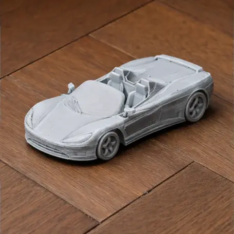 3D-printed model of a sporty, futuristic car with sleek curves, resting on a wooden surface.
