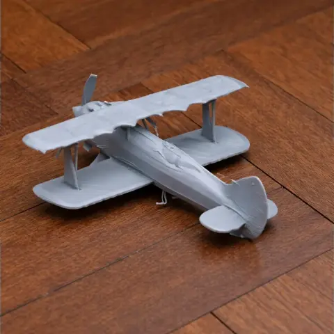 3D printed model of a biplane with dual wings and propeller, displayed on a wooden surface.