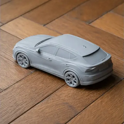 3D-printed model of a sleek, modern sedan, displayed on a wooden surface.
