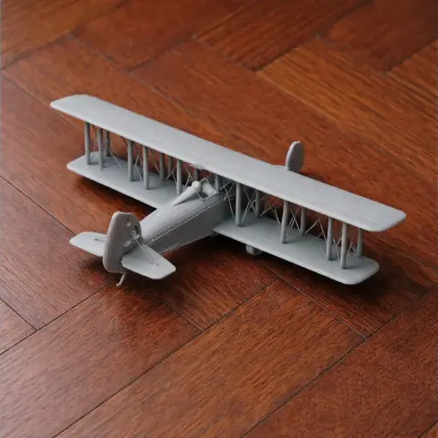 A scale model of a biplane with detailed wings and tail, placed on a wooden floor.