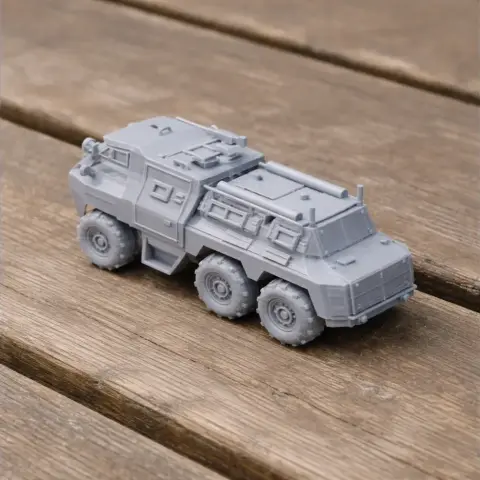 Gray 3D-printed model of a six-wheeled armored personnel carrier on a wooden surface.