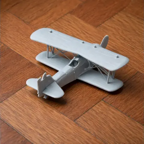 Gray 3D printed model of a Curtiss F7C Seahawk biplane on a wooden floor.