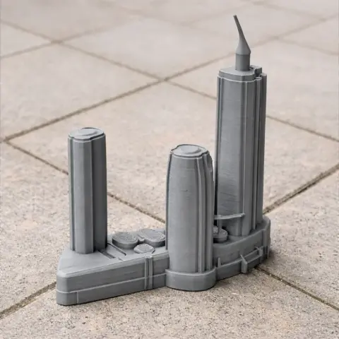 A 3D printed model of futuristic skyscrapers on a triangular base, placed on a tiled surface.