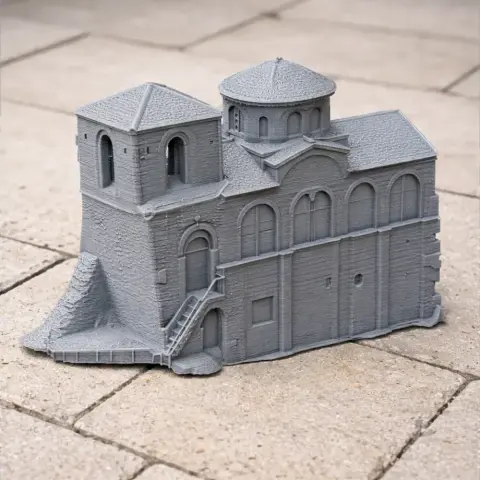 Gray 3D-printed model of a medieval fortress with towers and arches on a tiled surface.