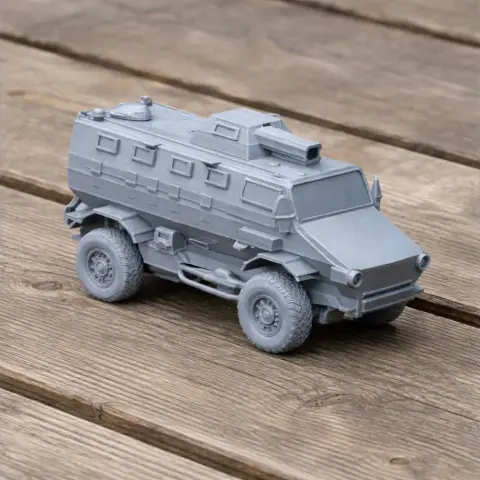 Gray 3D printed model of an armored military vehicle with six wheels on a wooden surface.