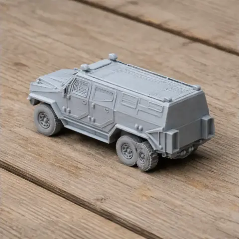 3D printed model of a light armored military vehicle on a wooden surface.