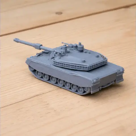 Miniature 3D-printed model of a Type 88 tank, gray, detailed with a turret and tracks, on a wooden surface.