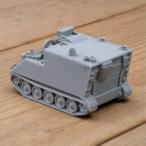 3D-printed model of an M577A4 armored treatment vehicle with tracked wheels on a wooden surface.