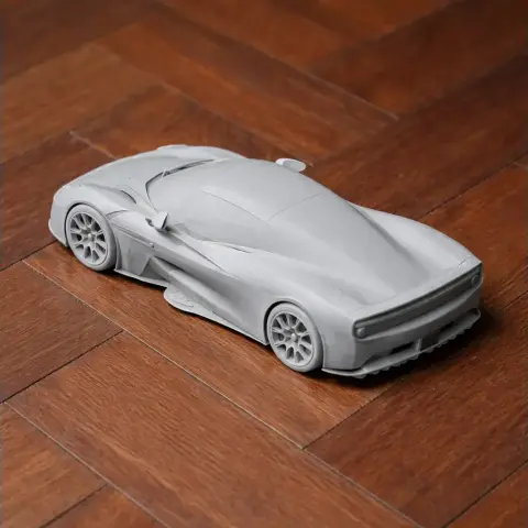 3D printed model of a sleek, aerodynamic sports car on a wooden surface.