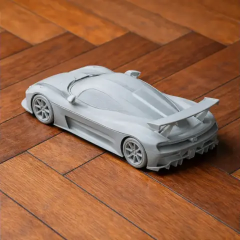 Gray 3D-printed model of a Dallara Stradale car on a wooden surface.