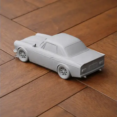 3D-printed model of a Datsun SR311 sports car on a wooden surface.