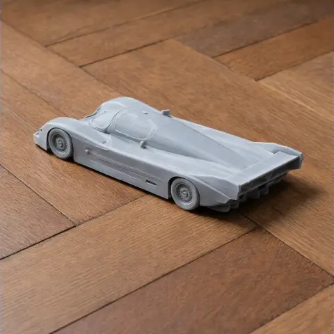 3D-printed model of a sports car on a wooden surface, featuring sleek aerodynamic design.
