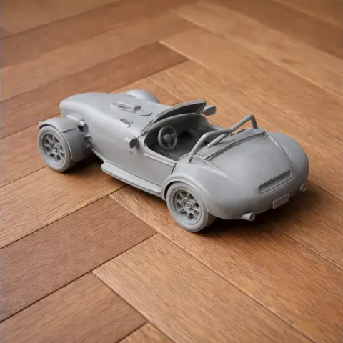 3D-printed model of a vintage sports car on a wooden floor.