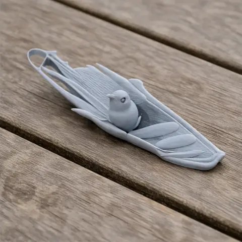 3D printed model of a bird resting on a leaf, placed on a wooden surface.