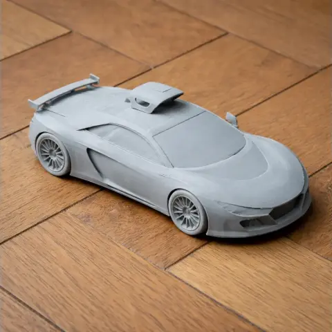 3D printed model of a sleek, aerodynamic sports car with a rear spoiler, placed on a wooden floor.