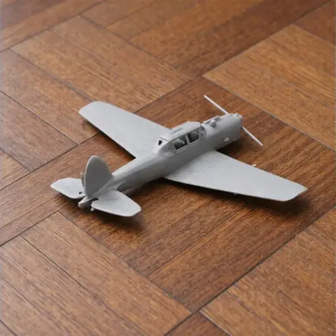 Gray 3D printed model of a De Havilland Canada DHC-1 Chipmunk airplane on a wood surface.