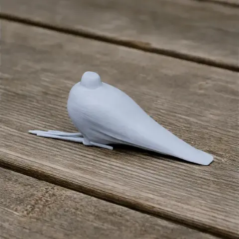 White 3D-printed bird model, with a smooth finish, resting on a wooden surface.