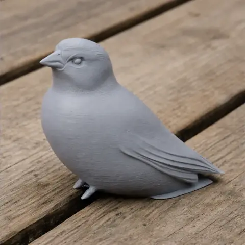 3D printed gray bird model on a wooden surface, featuring detailed feathers and a smooth finish.