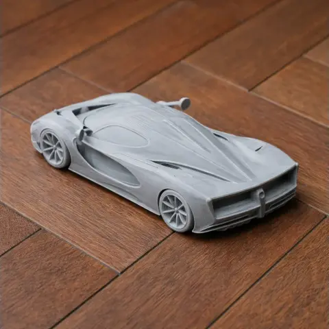 3D printed model of a sleek, modern De Tomaso P72 car on a wooden surface.