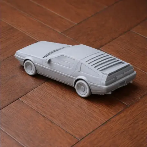 3D printed gray model of a DeLorean DMC-12 car on wooden floor.