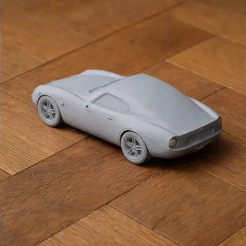 3D printed model of a vintage sports car on a wooden surface.